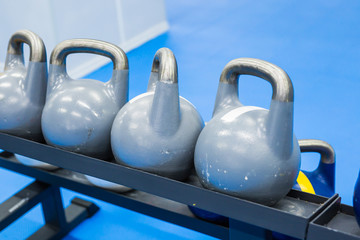 Naklejka na ściany i meble Blue kettlebells in a row in a gym - focus on the front kettlebell
