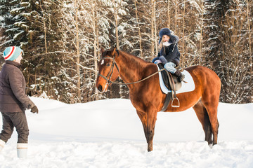 Fototapeta na wymiar Small girl, horse trainer and horse in a winter