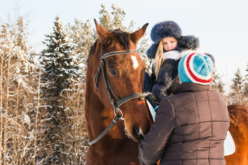 Fototapeta premium Small girl, horse trainer and horse in a winter