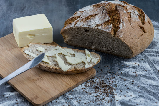 Fresh homemade bread with cumin and sunflower seeds on a wooden cutting board and a bit of risky flour