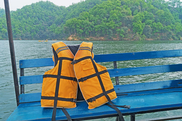 Yellow-orange lifejacket on a ship against the backdrop of the coastline.