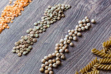 Decorations made of red and brown lentils, whole-grain pasta and chickpeas on a wooden background