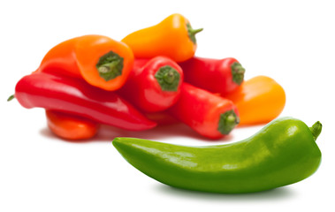 Green pepper and heap of red and orange over white