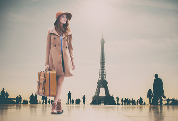 Fototapeta na wymiar Redhead girl with suitcase and Eiffel tower