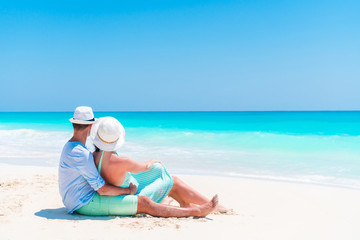 Fototapeta na wymiar Young couple on white beach during summer vacation. Happy lovers enjoy their honeymoon