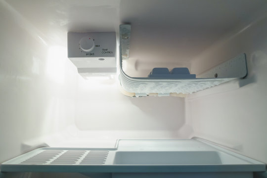 Empty open of small refrigerator with ice buildup on the freezer.