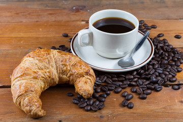 Breakfast with coffee and croissant on wooden table