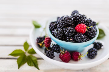 Fresh blackberries in bowl on wooden table in the garden.