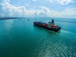 container ship in import export and business logistic.By crane , Trade Port , Shipping.Tugboat assisting cargo to harbor.Aerial view.