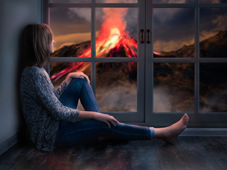 The girl looks out the window at a natural disaster - the eruption of the volcano