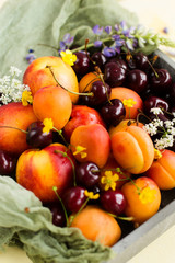 Fruit in a box decorated with flowers on a yellow background (close-up)
