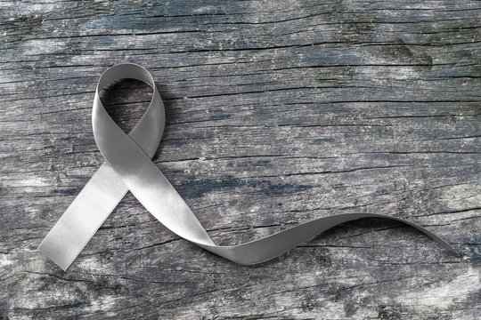 Silver color ribbon on old aged wood (isolated with clipping path) for Parkinson's disease awareness and Brain cancer tumor illness