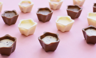 Various chocolate pralines on pink background.