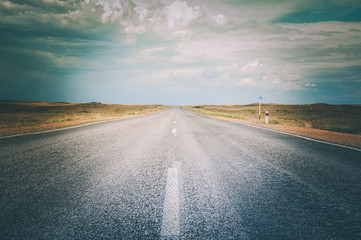 Asphalt straight road and blue sky with clouds above . Concept photo. Toned. - 163887902