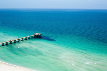 Pier jutting out into the ocean under clear blue skies