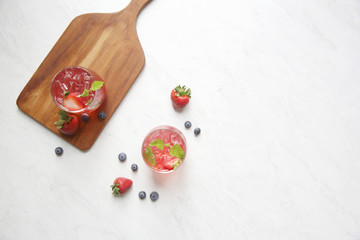 Strawberry juice cocktail with ice and mint on white tone amd wooden