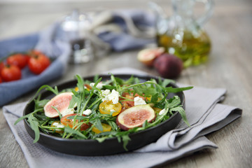 Fresh salad with arugula tomato and cheese on wooden background