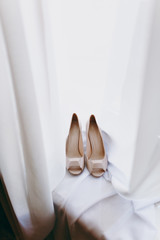 Fototapeta na wymiar Bride wedding shoes with high heels and silver brilliant earrings on sheep's clothing