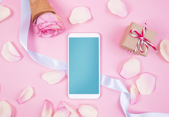 Mobile phone device with rose decoration on pastel pink background