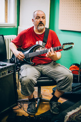 Obraz premium Behind scene. Guitarist practice playing guitar in messy music studio
