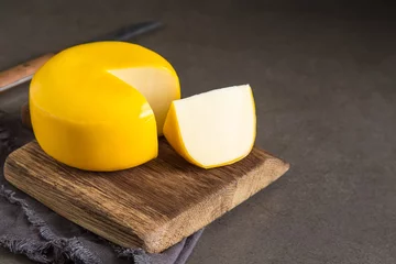 Fotobehang Round gouda cheese. Dark background. © naltik