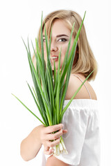 Naklejka premium Portrait of Beautiful blond woman holding green onion on white background. Health and vitamins