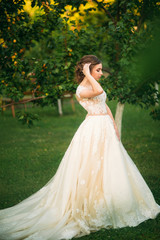Young girl in wedding dress in park posing for photographer.