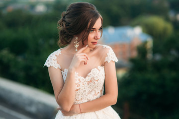 Young girl in wedding dress on city background at sunset.