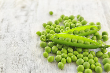 Fresh green peas on white wooden background