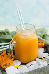 Apricot juice with ice in a jar on a blue background (close-up)