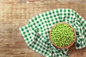 Bowl with fresh green peas on wooden table