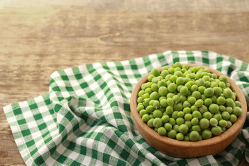 Bowl with fresh green peas on wooden table