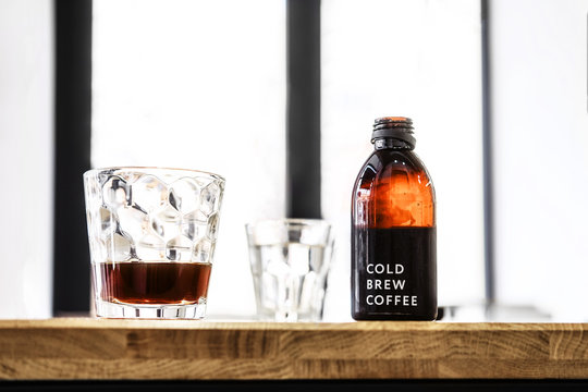 Filter cold brew coffee bottle and glass on a wooden table. Loft design