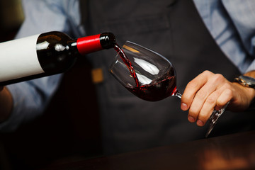 Man pouring wine into wineglass, male hand holding bottle © Ilshat