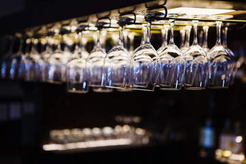 Empty wine glasses hanging upsidedown in bar interior.