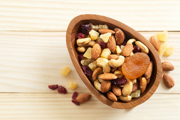 mixed nuts and dried fruit in wooden bowl on wooden table top view. Walnut, pistachio, almond, hazelnut, cashews, apricot, berry, banana, pineapple, Healthy food and snack