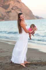 Fototapeta na wymiar Happy mother with a small girl walking on a beach