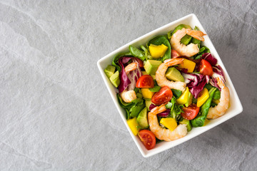 Shrimps salad with mango and avocado on gray stone
