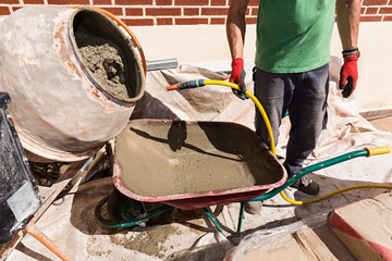 Obrero trabajando, haciendo cemento, con la manguera en la mano.