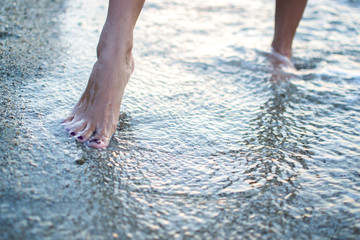 Close up of woman legs walking on the beach.