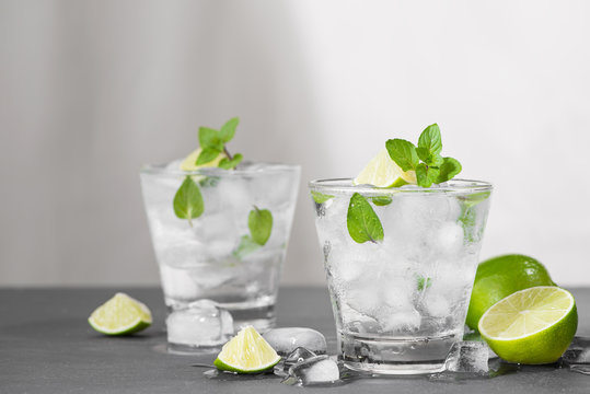 Mojito cocktail with lime and mint in glass on a grey stone background