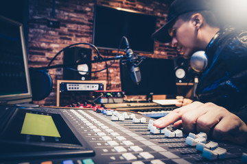 music producer working on sound mixer in recording studio or DJ working in broadcasting studio