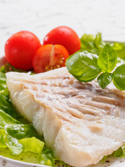 Close up grilled codfish with basil and cherry tomatoes