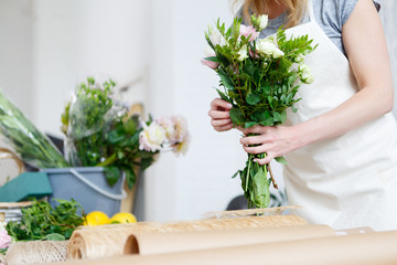 Obraz na płótnie Canvas Young woman florist makes bouquet
