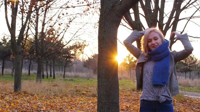 Young woman happiness hidden among the autumn colorful leaves in sunset