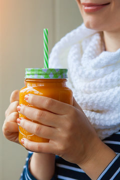 Girl holding a jar with a smoothie made from carrots and pumpkin. Woman drinking vegetable juice for weight loss. Diet, detox.