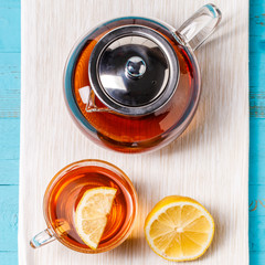 Glass cup of tea with lemon and glass teapot.