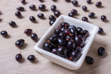 black currant in glassware on white wooden table top view