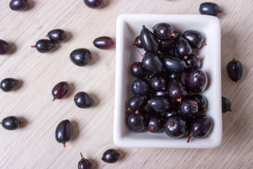 black currant in glassware on white wooden table top view