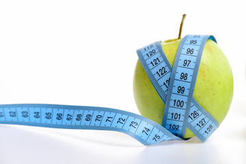 Long tape for measuring in blue colour wrapped around apple